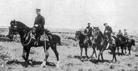 Photographie ancienne d'officiers à cheval en terrain découvert, l'un au premier plan sabre au flanc