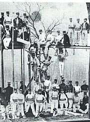 Photographie ancienne de militaires en tenue de gymnastique posant sur un portique d'exercice en bois