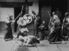 Document d'archive reproduit dans le recueil Photographie ancienne d'un assaut au shinaï en tenue d'entraînement devant un dojo orné d'un blason tomoe