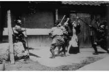 Acteurs japonais : bataille au sabre Vue N° 978 Scène de combat au sabre jouée par des acteurs japonais devant une maison, vue ancienne numérotée 978